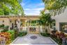 Covered lanai featuring a stone-paver patio with decorative inlay, built-in outdoor kitchen with stainless steel ventilation hood, and heavy-timber be
