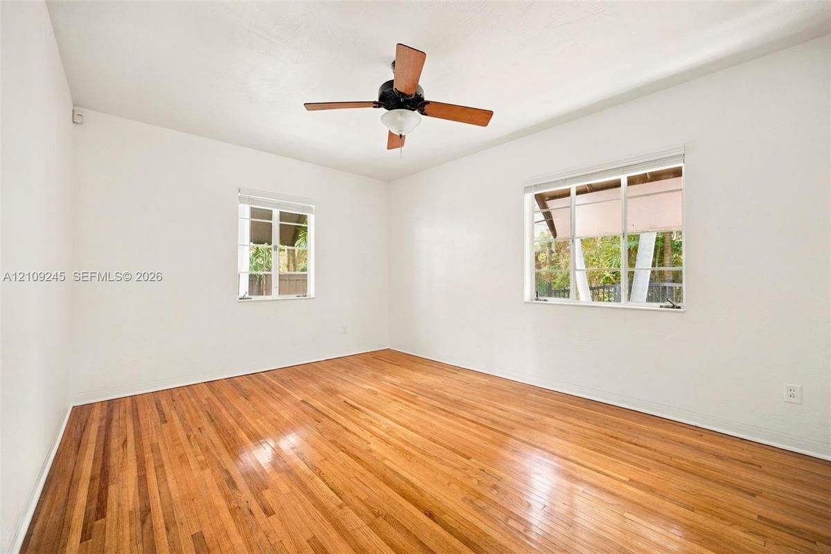 Room featuring wood-finish flooring, multi-pane windows, and a ceiling fan with integrated lighting