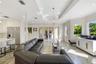 Open-concept living space featuring high ceilings with crown molding, recessed lighting, geometric metal pendant fixture, large-format tile flooring, 