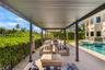 Covered outdoor patio featuring a metal pergola, large-format tile flooring, in-ground pool, and a metal perimeter fence