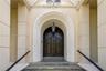 Double arched solid wood doors featuring brass lion-head knockers, set within a recessed masonry entryway with decorative molding, stone-stepped riser