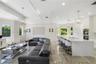 Open-concept interior featuring large-format tile flooring, a waterfall-edge stone island with integrated cooktop, dual built-in wall ovens, recessed 