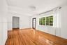 Living space featuring polished wood-finish flooring, a large multi-pane window, an arched doorway, and a glass-paneled exterior door