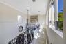 Hallway featuring large-format tile flooring, ornate wrought-iron railings, high ceilings with recessed lighting, and a multi-tiered crystal chandelie