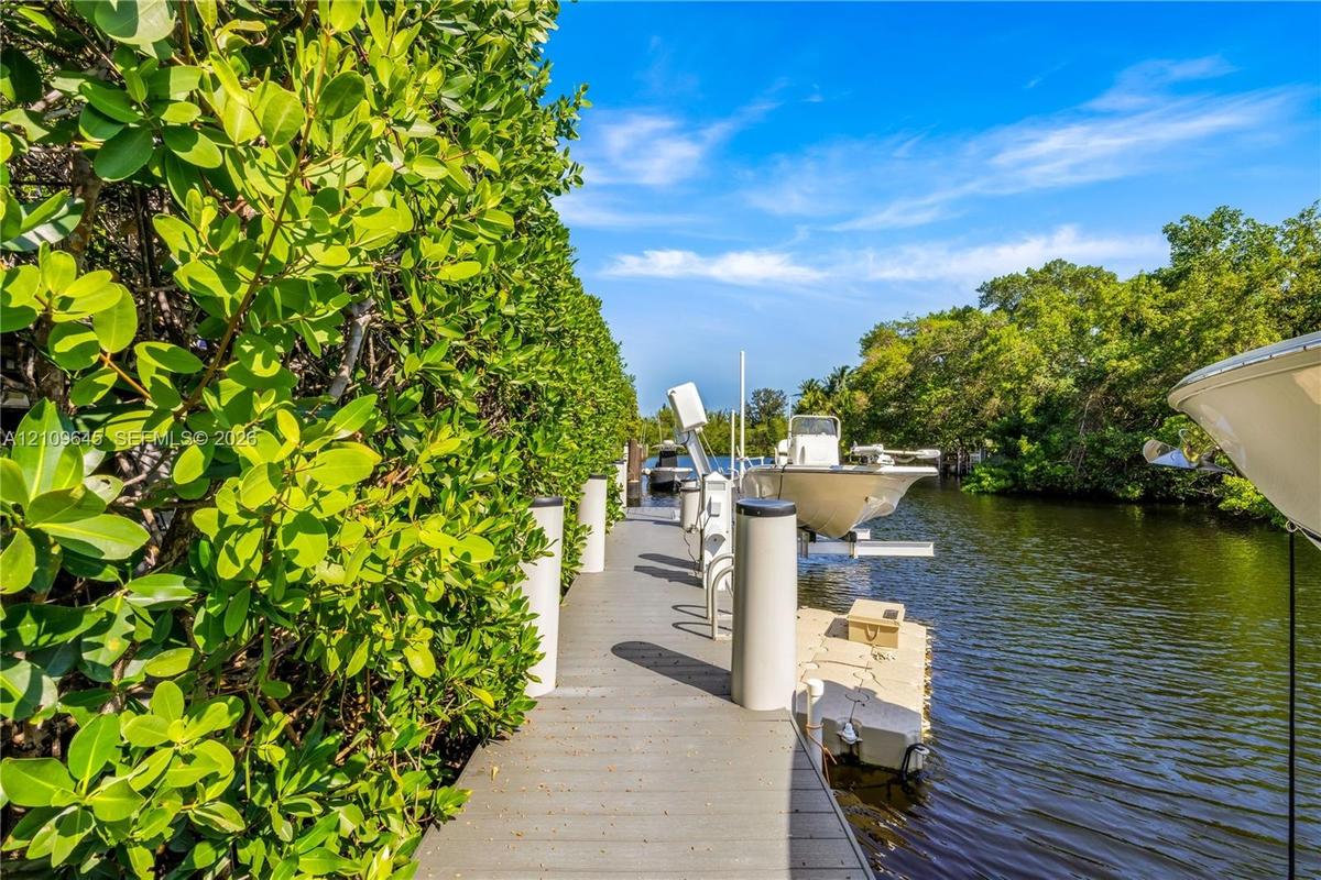 Waterfront dock featuring composite decking, vertical pilings, and a mechanical boat lift