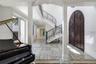 Foyer featuring arched double entry doors, curved staircase with ornamental metal railings, stone flooring with linear patterns, recessed lighting, an