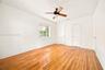 Room featuring wood-finish flooring, a multi-pane window, and a ceiling-mounted light fixture with a fan