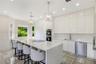 Modern kitchen featuring high-gloss cabinetry, stone-finish countertops, an oversized center island, built-in stainless steel appliances, and patterne