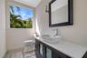 Modern vanity featuring a stone countertop, vessel sink, and metallic hardware, complemented by patterned tile flooring and a wall-mounted light fixtu
