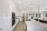 Kitchen featuring high-gloss cabinetry, stone-surfaced center island with integrated cooktop, built-in stainless steel double ovens, recessed lighting