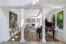 Open floor plan featuring wood-finish flooring, tray ceilings, a central stone-surround fireplace, and large picture windows