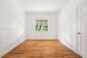 Interior room featuring wood-finish flooring, white walls, and a multi-pane window with a neutral roller shade