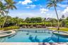 In-ground swimming pool with built-in wading stools and integrated spa, complemented by a stone-paved pool deck, covered pergola structure, and mature