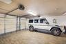 Garage featuring wood-finish flooring, dual motorized garage door openers, and rectangular LED light fixtures
