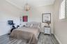 Room featuring wood-finish flooring, crown molding, a decorative orb chandelier, built-in shelving, and an arched window with plantation shutters
