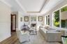 Living area featuring wood-finish flooring, a tray ceiling with crown molding, a wood-burning fireplace with a mantel, and oversized windows