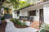 Exterior featuring white stucco siding, a terracotta-tiled front porch, black metal railings, and a curved concrete walkway