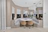 Custom built-in upholstered banquette seating, floor-to-ceiling wall mirror, bay window configuration with integrated blinds, and polished pendant lig