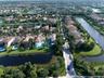 Aerial perspective of a residential neighborhood featuring waterfront lots, multi-story dwellings, tile roofing, and integrated canal systems