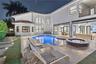 Stucco exterior featuring a resort-style pool, raised spa with tile surround, natural stone paver patio, and covered outdoor living area