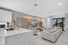 Kitchen featuring a waterfall-edge island with a stone-finish countertop, white cabinetry, integrated under-cabinet lighting, and large-format tile fl