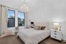 Room with wood-finish flooring, dual windows with dark frames, and a decorative crystal chandelier