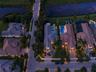 Aerial perspective of residential properties featuring tile roofing, paved driveways, private swimming pools, and landscaped perimeters situated along