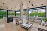Covered outdoor living space featuring natural stone flooring, wood-plank ceiling, recessed lighting, and a built-in outdoor kitchen with a dark-toned