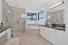 Bathroom featuring a double vanity with stone countertops, a corner soaking tub, and a glass-enclosed shower with tiled surround