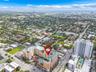 Aerial perspective of a multi-story residential building featuring a sprawling outdoor pool deck, terraced balconies, and a distinctive peaked rooflin
