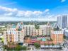 Multi-story high-rise building featuring a structured facade, gabled rooflines, recessed balconies, an elevated outdoor swimming pool, and manicured t