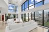 Double-height ceiling, floor-to-ceiling windows, polished stone flooring, custom crystal chandelier, and integrated exterior terrace