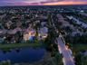 Aerial perspective of a residential neighborhood featuring waterfront lots, paved roadways, mature palm trees, and rear-yard swimming pools