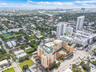 High-rise residential complex featuring a podium-level swimming pool, terra cotta facade, pitched green roofing, and ground-level retail space
