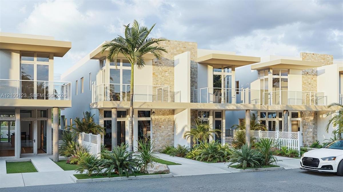 Contemporary multi-unit exterior featuring stacked stone accents, second-story glass-railed balconies, floor-to-ceiling windows, and concrete walkways