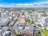 Aerial perspective of a high-rise urban center featuring multi-story residential buildings, commercial structures, structured parking facilities, and 