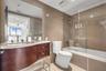 Bathroom featuring a curved vanity with stone countertop, horizontal tile wall accents, and a glass-enclosed shower and tub combination