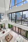 Double-height vaulted ceilings featuring floor-to-ceiling multi-story windows, polished stone flooring, intricate tiered crystal chandelier, and direc
