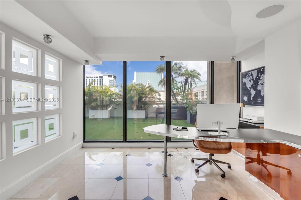 Floor-to-ceiling windows, stone tile flooring with decorative inlay, built-in high-gloss cabinetry, recessed ceiling lighting, and custom geometric gl