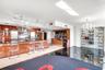 Modern kitchen featuring high-gloss cabinetry, dark stone countertops, built-in stainless steel appliances, a recessed wet bar, and a floor-to-ceiling