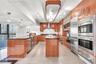 Contemporary kitchen featuring high-gloss cabinetry, stone countertops, double wall ovens, integrated stainless steel refrigeration, and a central isl