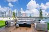 Expansive rooftop terrace featuring wood-plank decking, synthetic turf, integrated wall-mounted lighting, and panoramic urban skyline scenery
