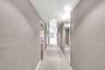 Hallway featuring matte grey paneling with horizontal reveals, inset floor-to-ceiling mirrored walls, and recessed ceiling lighting
