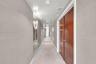Hallway featuring large-format light gray wall panels, full-height wall mirrors, double-door wood cabinetry, and recessed lighting