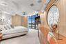 Floor-to-ceiling windows with panoramic exterior exposure, curved architectural ceiling detail, built-in cabinetry with high-gloss finish, circular wa