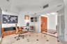 Light-filled room featuring large-format stone flooring with decorative inlay, custom wood-finish built-in cabinetry, frosted glass pivot entry doors,