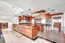 Gourmet kitchen featuring high-gloss wood cabinetry, dark stone countertops, integrated stainless steel appliances, a glass-top breakfast bar, and pol