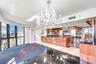 Kitchen featuring high-gloss wood cabinetry, dark stone countertops, built-in stainless steel appliances, a large center island, and an ornate crystal