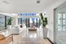 Expansive living area featuring floor-to-ceiling windows, polished stone flooring, and a glass-panel door