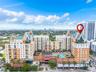 Multi-story residential complex featuring steep-pitched roof gables, stucco facade, integrated swimming pool, and lush perimeter landscaping